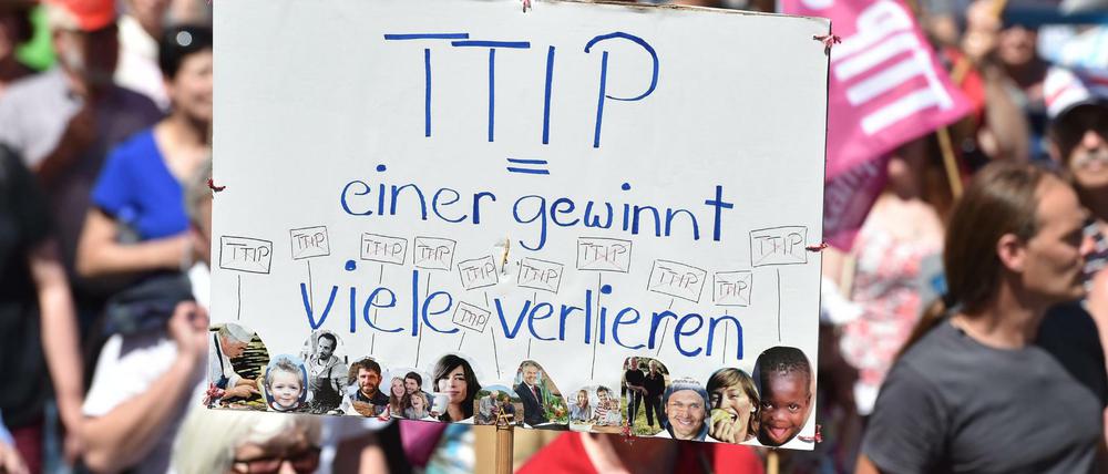 Demonstranten halten am 04.06.2015 in München (Bayern) bei einer Demonstration gegen den G7-Gipfel ein Schild mit dem Schriftzug "TTIP - einer gewinnt - viele verlieren".