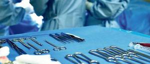 Hier erklingt Musik. Chirurgen beugen sich über den Operationstisch, im Vordergrund liegt das OP-Besteck bereit.