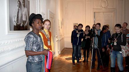 Zanele Muholi (links) bei einer Ausstellungseröffnung. Im Hintergrund eines ihrer Porträts.