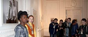 Zanele Muholi (links) bei einer Ausstellungseröffnung. Im Hintergrund eines ihrer Porträts.