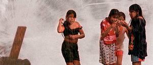 Kinder spielen an geöffnetem Hydranten