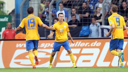 Braunschweigs Adam Matuschyk (Mitte) jubelt über seinen Treffer zum 0:1 mit seinen Teamkollegen Ken Reichel (links) und Emil Berggreen.