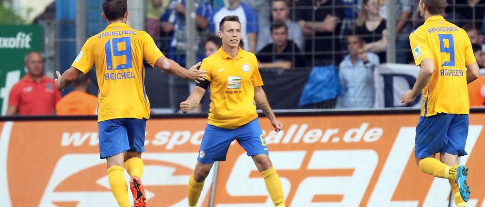 Braunschweigs Adam Matuschyk (Mitte) jubelt über seinen Treffer zum 0:1 mit seinen Teamkollegen Ken Reichel (links) und Emil Berggreen.