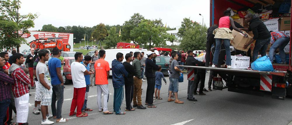 Flüchtlinge stehen in Heidenau auf einem Willkommensfest an einem LKW Schlange, um gespendete Sachen entgegenzunehmen.