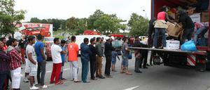 Flüchtlinge stehen in Heidenau auf einem Willkommensfest an einem LKW Schlange, um gespendete Sachen entgegenzunehmen. 