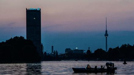 Ein Motorboot fährt abends auf der Spree. Im Hintergrund sind Allianz-Tower und der Fernsehturm zu sehen.