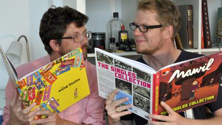 Mawil (links) und Flix beim Vergleichen ihrer druckfrischen Bücher in Flix’ Atelier. Unten zwei Zeichnungen der beiden, mit denen für die Buchvorstellung am Donnerstag geworben wird. Motto: „Fesche Singles und schöne Töchter“.