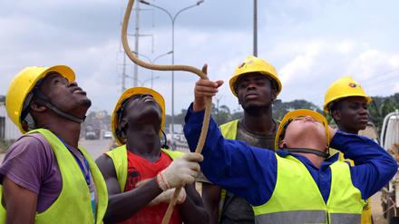 Das rohstoffhungrige China investierte viele Jahre lang kräftig in Afrika. Das ändert sich. Zudem macht der Ölpreis Probleme. Das Foto zeigt einen Mitarbeiter des Konzerns Power China mit Arbeitern an der Elfenbeinküste.