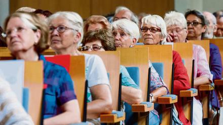 In einem Hörsaal sitzen ältere Frauen und Männer und blicken nach vorne.