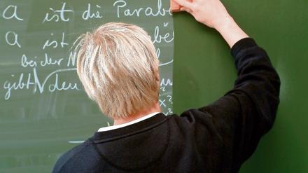 Ein Lehrer wischt während des Mathematik-Unterrichts die Tafel sauber.