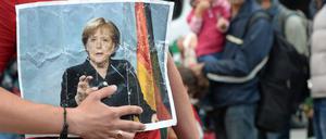 Ein Flüchtling hält am Bahnhof München ein Bild von Angela Merkel in der Hand.