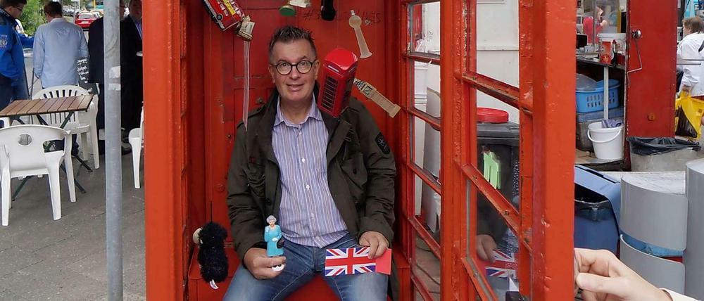 Ein Englishman in Berlin: Michael Hughes hat die rote Telefonzelle am Fehrbelliner Platz mit Souvenirs bestückt, die er für seine Fotos nutzt.