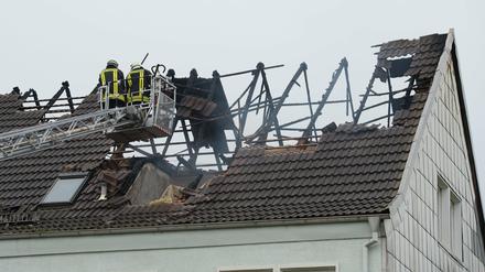 Einsatzkräfte der Feuerwehr stehen am 07.09.2015 in Ebeleben (Thüringen) nach einem Brand in einer künftigen Flüchtlingsunterkunft auf einer Drehleiter. Der Wohnblock wurde derzeit für die Unterbringung von Asylsuchenden saniert. 