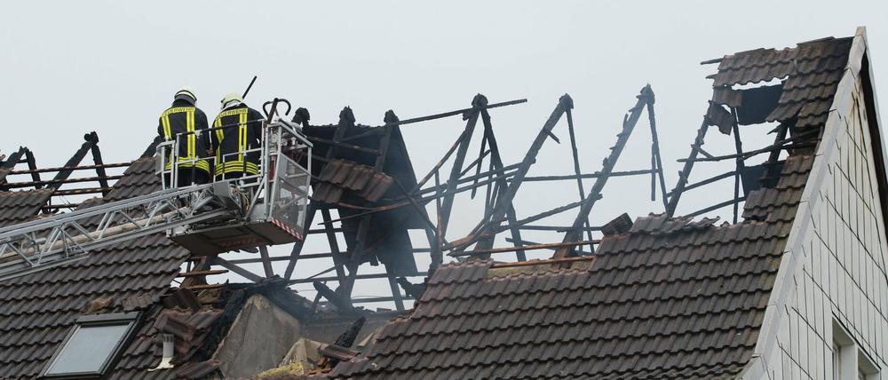 Einsatzkräfte der Feuerwehr stehen am 07.09.2015 in Ebeleben (Thüringen) nach einem Brand in einer künftigen Flüchtlingsunterkunft auf einer Drehleiter. Der Wohnblock wurde derzeit für die Unterbringung von Asylsuchenden saniert. 