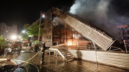Feuerwehrleute sind am Dienstag mit Nachlöscharbeiten an der West-Bühne auf dem Spielbudenplatz in Hamburg beschäftigt. Bei einem Brand an der Hamburger Reeperbahn ist am frühen Dienstagmorgen eine Veranstaltungsbühne komplett zerstört worden. Wie die Polizei mitteilte, stand aus noch ungeklärter Ursache die West-Bühne auf dem Spielbudenplatz in Flammen.