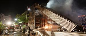 Feuerwehrleute sind am Dienstag mit Nachlöscharbeiten an der West-Bühne auf dem Spielbudenplatz in Hamburg beschäftigt. Bei einem Brand an der Hamburger Reeperbahn ist am frühen Dienstagmorgen eine Veranstaltungsbühne komplett zerstört worden. Wie die Polizei mitteilte, stand aus noch ungeklärter Ursache die West-Bühne auf dem Spielbudenplatz in Flammen.