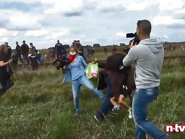 Eine Kamerafrau des ungarischen Senders N1TV stellt in Röszke einem Flüchtling, der ein kleines Kind auf dem Arm trägt, ein Bein.