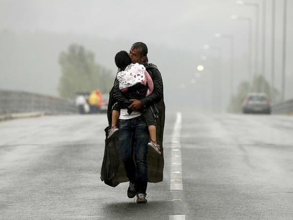 Ein syrischer Flüchtling mit seiner Tochter im Regen an der Grenze zwischen Mazedonien und Griechenland.