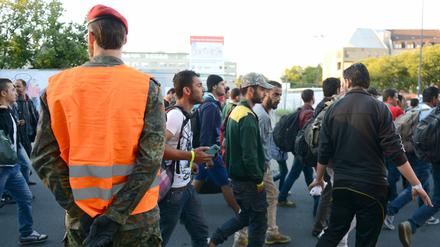 Ein Bundeswehrsoldat steht am Bahnhof in Dortmund nach der Ankunft eines Sonderzuges mit Flüchtlingen und weist den Weg.