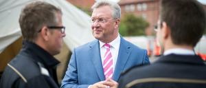 ARCHIV - Frank Henkel (M, CDU), Berliner Innensenator, unterhält sich am 03.09.2015 auf dem Gelände der ehemaligen Schmidt-Knobelsdorf-Kaserne der Polizei in Berlin-Spandau mit Feuerwehrleuten über die Situation in der Flüchtlingsunterkunft. 