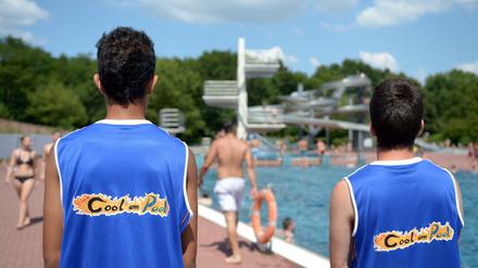 Zwei junge Männer beobachten am 23.07.2014 im Sommerbad Pankow in Berlin das Treiben am Sprungturm. Seit vier Jahren helfen Konfliktlotsen von "Bleib cool am Pool" im Columbiabad Neukölln dabei, kleinere Streitigkeiten friedlich zu lösen.