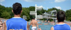 Zwei junge Männer beobachten am 23.07.2014 im Sommerbad Pankow in Berlin das Treiben am Sprungturm. Seit vier Jahren helfen Konfliktlotsen von "Bleib cool am Pool" im Columbiabad Neukölln dabei, kleinere Streitigkeiten friedlich zu lösen.