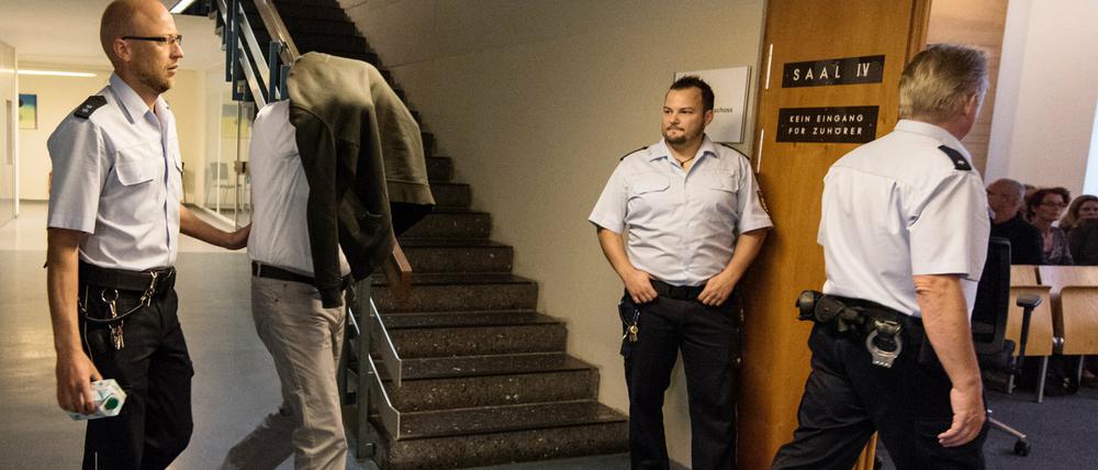 Der Angeklagte (2.vl) kommt am Dienstag mit einer Jacke über dem Kopf von Wachtmeistern begleitet ins Landgericht in Freiburg. Dem 33 Jahren alten Stiefvater wird vorgeworfen, den dreijährigen Alessio im Januar 2015 auf einem Bauernhof in Lenzkirch zu Tode geprügelt zu haben.