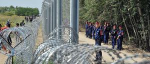 Hüben und drüben. Flüchtlinge laufen nahe der nordserbischen Stadt Horgos auf serbischer Seite an der mit Stacheldraht gesicherten Grenze entlang, an der auf ungarischer Seite Polizisten aufmarschiert sind. 
