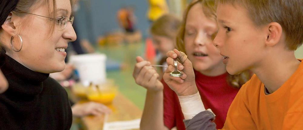 Probieren und studieren: Zwei Kinder testen gefärbten Jogurt beim Projekt "ScienceKids".