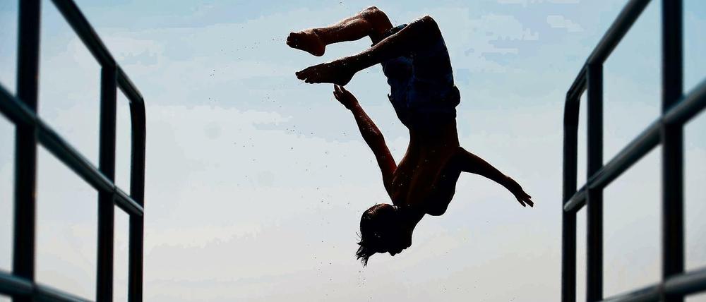 Ein Junge springt am 20.06.2013 von einem Sprungbrett am Freibad in Storkow (Brandenburg) in das Wasser des Storkower Sees.