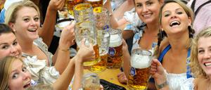 Frauen im Dirndl trinken in einem Festzelt auf dem Oktoberfest in München Bier. 
