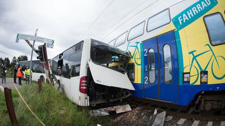 Ein Zug steht nach einem Zusammenstoß mit einem Schulbus auf den Gleisen. Bei dem Unfall wurde ein Mensch leicht verletzt.