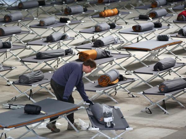 Jedes Bett wird gebraucht: Ein Helfer verteilt in einer Erstaufnahmestelle bei Hamburg Campingmatratzen und Schlafsäcke.