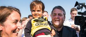 Bundeswirtschaftsminister Sigmar Gabriel (SPD) hält Muqnin, einen Flüchtlingsjungen aus Syrien, bei der Besichtigung des Flüchtlingslagers Saatari in Jordanien auf dem Arm. Links neben ihm Aydan Özoguz (SPD), Staatsministerin für Integration.