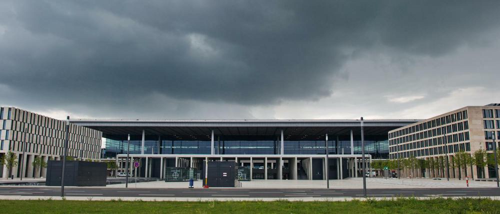 Dunkle Regenwolken liegen über dem Terminal des neuen Flughafens Berlin Brandenburg Willy Brandt (BER) in Schönefeld (Brandenburg).