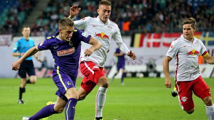 Dreikampf. Der Freiburger Stürmer Nils Petersen (l.) in Aktion gegen die Leipziger Stefan Ilsanker (Mitte) und Dominik Kaiser.
