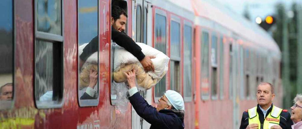 Eine ältere Frau reicht am Bahnhof in Freilassing (Bayern) einem mit einem Sonderzug aus Wien angekommenen Flüchtling eine von ihr gespendete Decke durch das Fenster des Waggons, bevor er nach einer kurzen Registrierung weiter nach Hanau fährt.