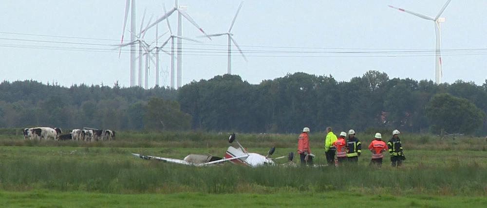 Feuerwehrleute neben einem abgestürzten Sportflugzeug auf eine Wiese nahe Sandstedt bei Cuxhaven (Niedersachsen). Drei Menschen kamen bei dem Unglück ums Leben.