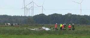 Feuerwehrleute neben einem abgestürzten Sportflugzeug auf eine Wiese nahe Sandstedt bei Cuxhaven (Niedersachsen). Drei Menschen kamen bei dem Unglück ums Leben. 