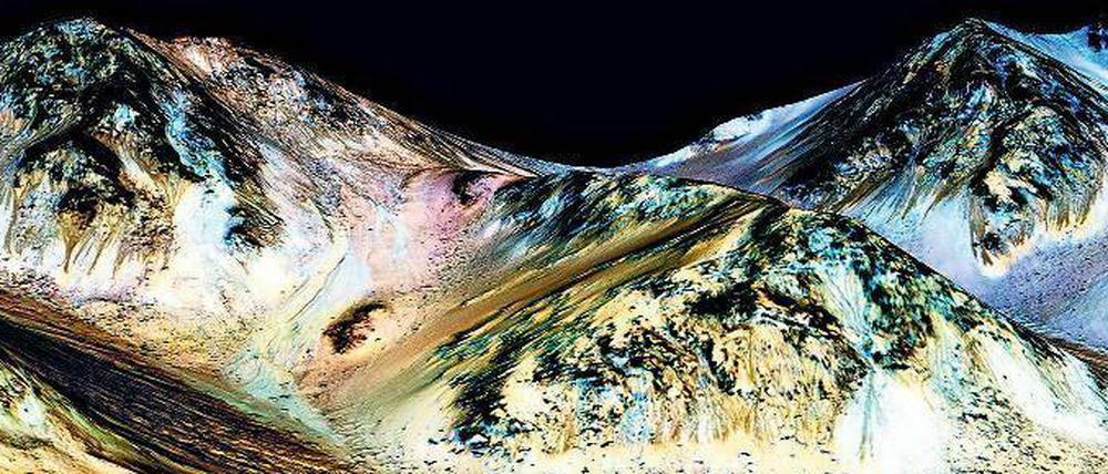 Farbenfroh. Die dunklen, etwa 100 Meter langen Fließstrukturen, die am Hale-Krater im Mars-Sommer sichtbar sind, sollen durch heute noch existierendes salziges Wasser entstanden sein. Was auf dem Bild blau angefärbt ist, ist allerdings kein Wasser, sondern mineralisches Pyroxen.