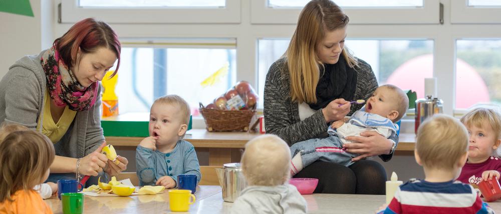 Die kleinsten Kinder des AWO Kindergartens «Diesterweg» in Lübbenau (Brandenburg) sitzen am 21.11.2014 beim Essen. Foto: Patrick Pleul/dpa (zu dpa «Tausende unterstützen Initiative für beitragsfreie Kita» vom 04.04.2015) +++(c) dpa - Bildfunk+++