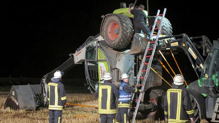 Feuerwehrleute versuchen einen Radlader zu bergen, der am 29.07.2014 auf einem Feld in Isselburg (Nordrhein-Westfalen) liegt. Ein tödlich verlaufender Video-Dreh für die Internetaktion "Cold-Water-Challenge" bringt zwei Männer aus dem Münsterland vor Gericht. Am Freitag beginnt in Bocholt der Prozess.
