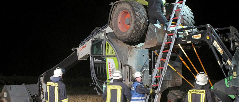 Feuerwehrleute versuchen einen Radlader zu bergen, der am 29.07.2014 auf einem Feld in Isselburg (Nordrhein-Westfalen) liegt. Ein tödlich verlaufender Video-Dreh für die Internetaktion "Cold-Water-Challenge" bringt zwei Männer aus dem Münsterland vor Gericht. Am Freitag beginnt in Bocholt der Prozess.