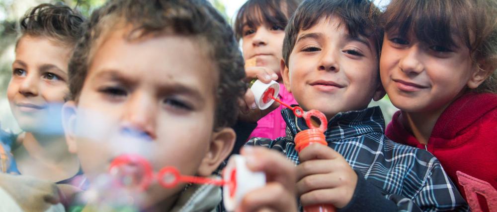 Flüchtlingskinder spielen auf dem Hof der Außenstelle des Landesamtes für Gesundheit und Soziales (Lageso) in einem ehemaligen Gefängnis in Berlin mit Seifenblasen.