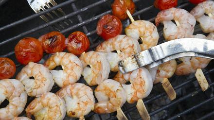 Scampi und Cocktail-Tomaten liegen beim Barbeque auf einem Grill.