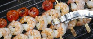 Scampi und Cocktail-Tomaten liegen beim Barbeque auf einem Grill.