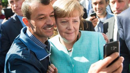 Ungewöhnlich nahbar. Bundeskanzlerin Angela Merkel (CDU) lässt sich am 10.09.2015 nach dem Besuch einer Erstaufnahmeeinrichtung für Asylbewerber in Berlin für ein Selfie zusammen mit einem Flüchtling fotografieren. 