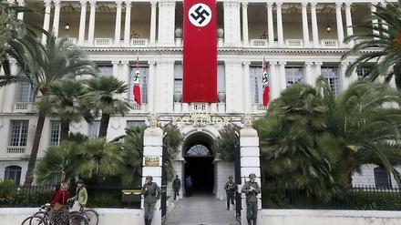 Eine Hakenkreuz-Fahne und die Wehrmacht vor dem Sitz der Präfektur in Nizza. 