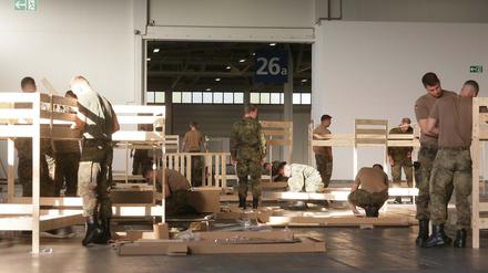 Soldaten der Bundesehr und Mitarbeiter des Malteser Hilfsdienstes bauen Betten für Flüchtlinge auf, die noch heute Nacht in der Messehalle 26 einziehen sollen.