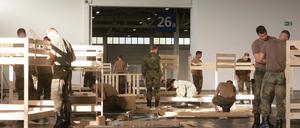 Soldaten der Bundesehr und Mitarbeiter des Malteser Hilfsdienstes bauen Betten für Flüchtlinge auf, die noch heute Nacht in der Messehalle 26 einziehen sollen.